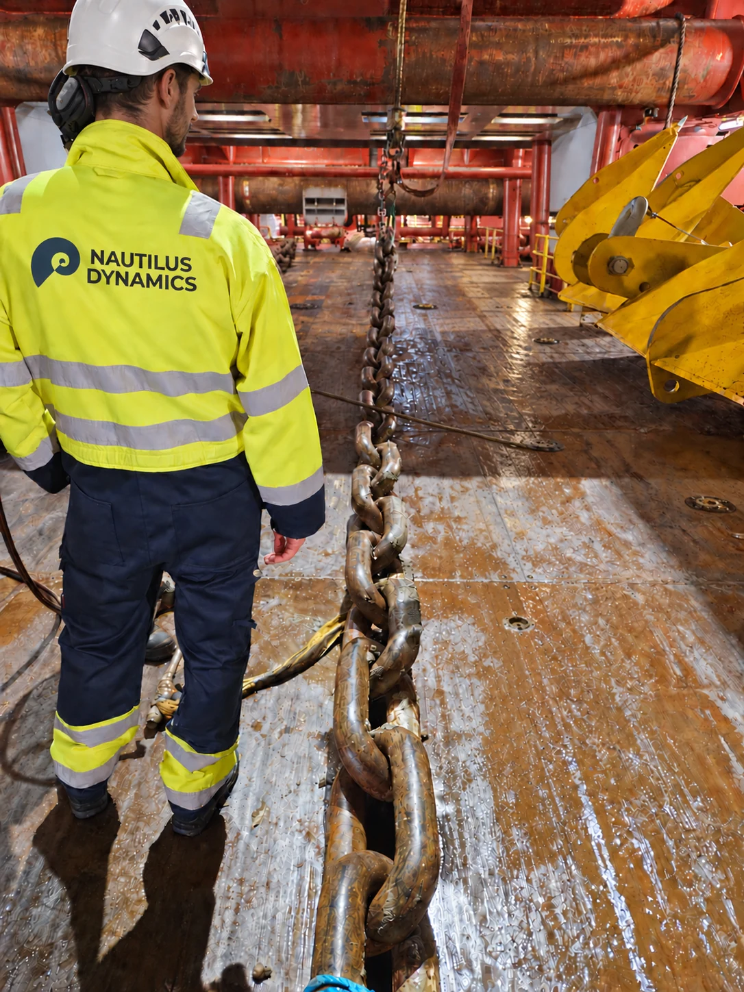 Offshore deck worker beside a mooring chain